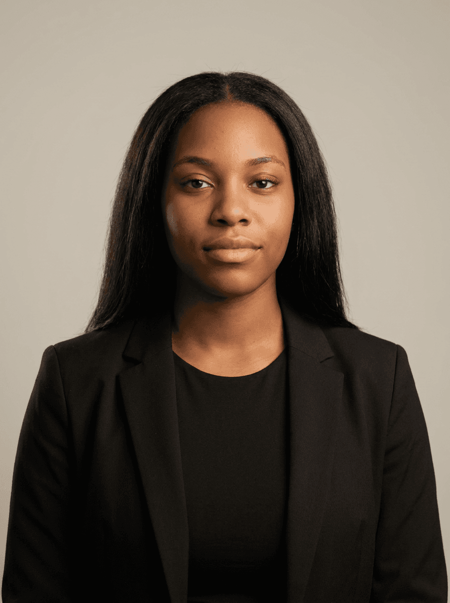 Example studio headshot of a woman, early 20s, Black Caribbean, a black blazer over a plain black top, on a light-grey backdrop